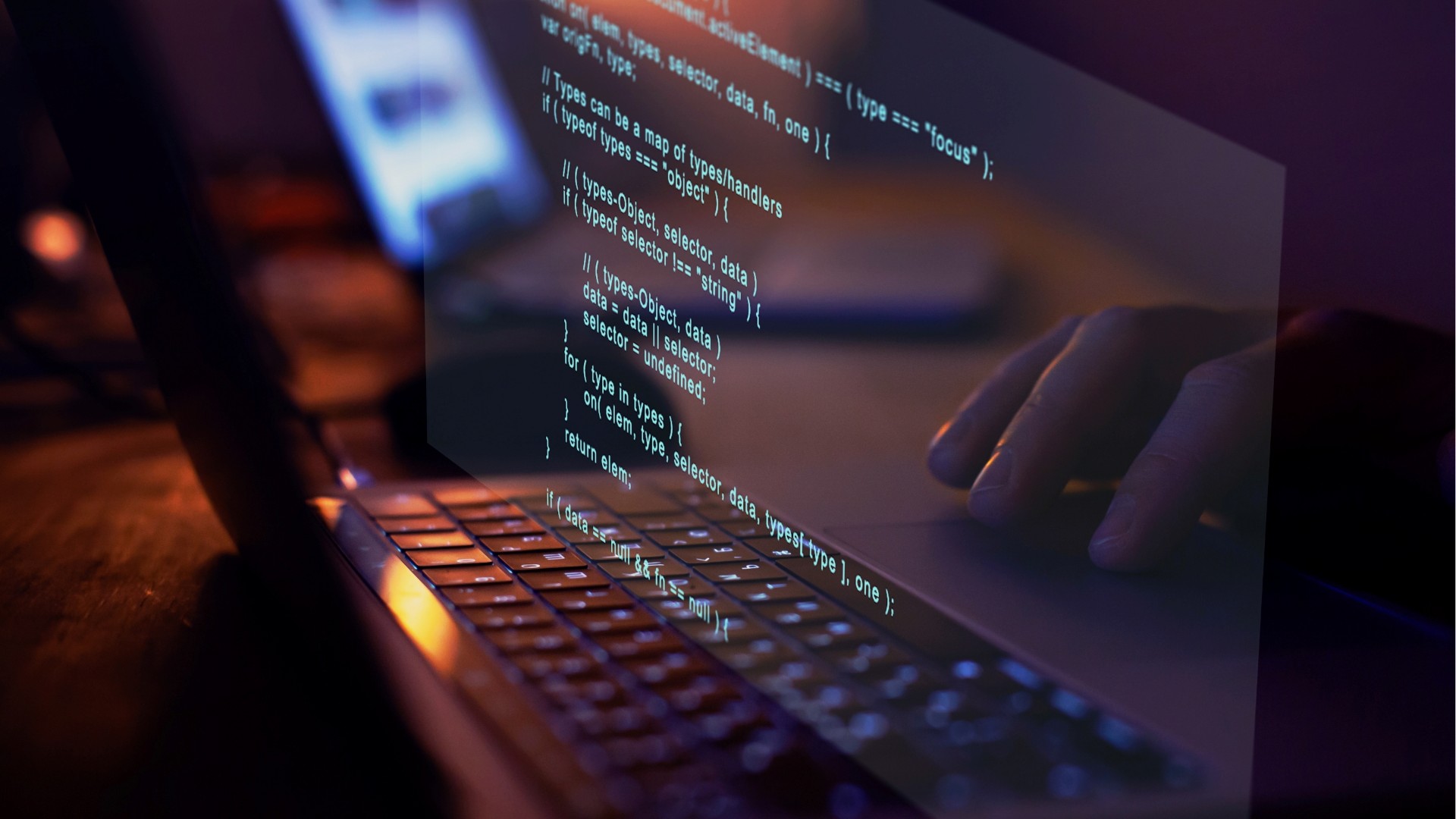 Hands typing on a laptop keyboard with computer code projected on the screen.